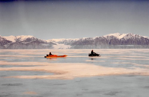 A snowmobile and qamutik leave Pond Inlet, 1994. (PHOTO BY JANE GEORGE)